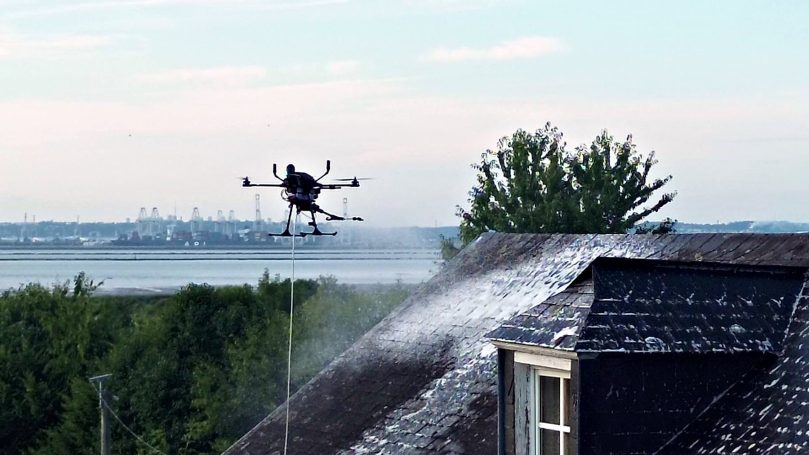 En vol face à l'estuaire Drone de nettoyage en vol au-dessus d'une toiture, estuaire en arrière-plan